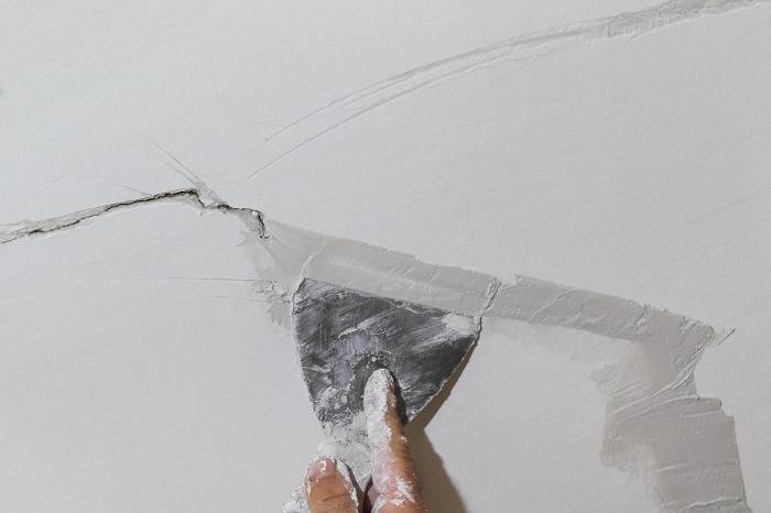 hand-holding-a-tool-applying-topcoat-to-a-crack-in-plasterboard